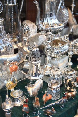 Parlak gümüş antikalar heykelcikler arasındaki ışığı yansıtıyor.