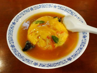 Tüylü omlet sebzelerle süslenmiş lezzetli kahverengi sosun üzerinde dinleniyor.