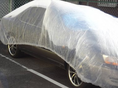 Otoparkta tek kullanımlık plastik araba kılıfı ile kaplı bir araba.