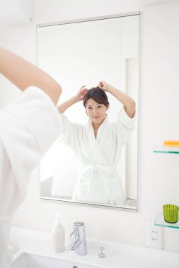 Genç, güzel Asyalı kadın banyoda günlük bakım rutinini yapıyor.