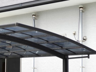 Konut duvarının yanında modern şeffaf garaj çatısı