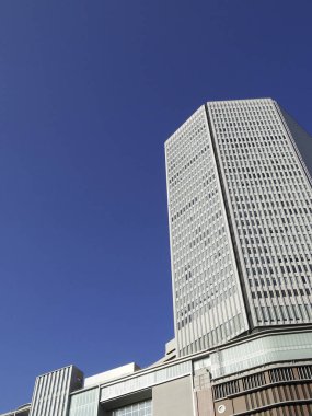 Mavi gökyüzüne karşı yüksek şehir binasının alçak açılı görüntüsü