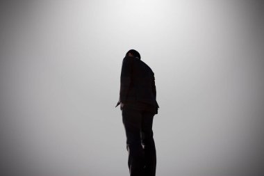 Işık arka planında duran bir adamın silüeti 