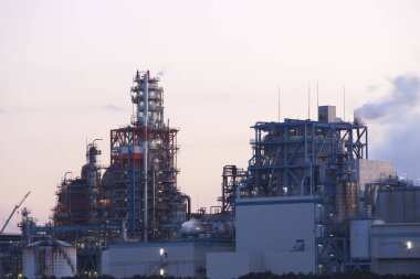 Arkaplanda akşam karanlığında petrol rafinerisi fabrikası