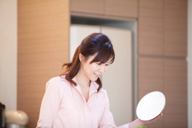 Mutfakta elinde ot kapağı olan Asyalı bir kadın.