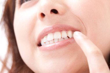 Genç Asyalı kadının açık arkaplanda dişlerini gösteren yakın plan portresi.