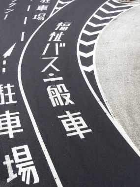 Eğri asfalt yol Japon park yeri işaretlerini gösteriyor.