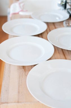 Tahta masanın üzerinde beyaz temiz tabaklar var.