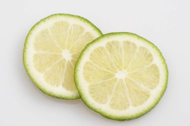 Beyaz zemin üzerindeki taze limon dilimlerinin yakın plan görüntüsü.            
