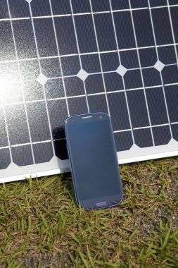 akıllı telefon ve yeşil çimenler üzerindeki güneş paneli 