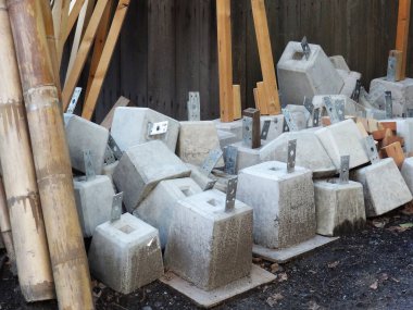 Dışarıdaki bambu direklerinin yanında istiflenmiş beton bloklar.