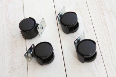 Beyaz ahşap arka planda Castor tekerlekleri olarak da bilinen dört döner kadro seti.