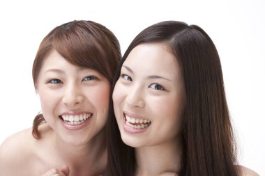 Beyaz arka planda gülümseyen genç Asyalı kadınlar 