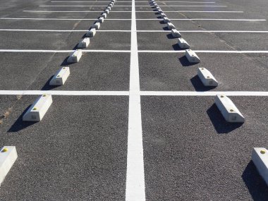 Boş otopark beyaz çizgiler ve beton bariyerler gösteriyor