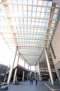 Şehir girişinde modern cam tepe örtüsü altında yürüyen insanlar