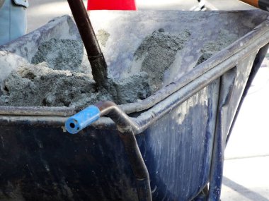 İnşaat sırasında mavi el arabasının içinde taze beton karışımı.
