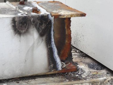 Yanık izleri ve ağır aşınma hasarı gösteren paslı metal kaplar.