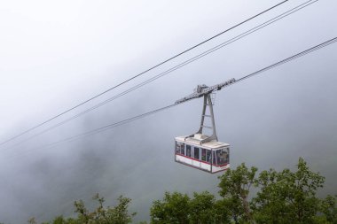 yeşil sisli dağlar arasında hareket eden teleferik