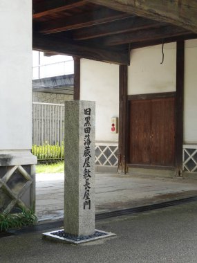 Geleneksel ahşap bina girişinin yanında duran taş sütun.