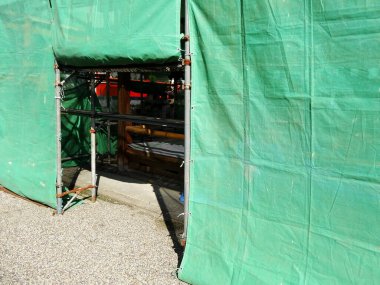 İskeleli ve açık girişi olan yeşil inşaat alanı