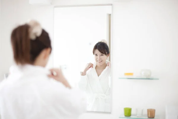 young Japanese woman looking in mirror at bathroom
