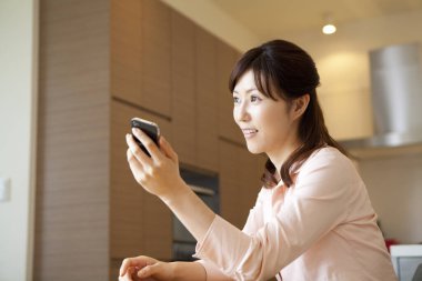 Güzel genç Asyalı kadın evde telefon kullanıyor.