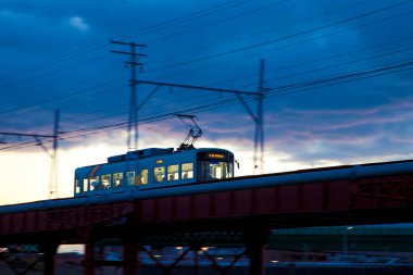 Japonya 'da gün batımında bir tren köprüsünden geçiyor.
