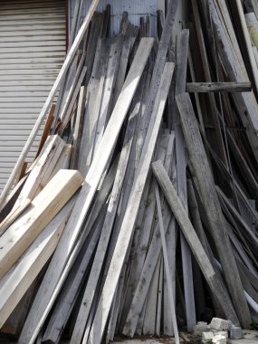 Yıpranmış ahşap kalasları, eğri büğrü metal duvarlara karşı dışarıda istifliyorum.