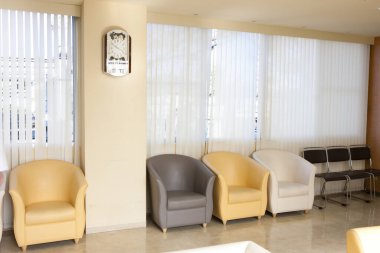 Geniş pencerelerin yanında koltuklar olan boş bekleme odası