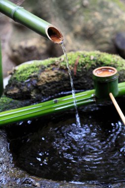 Bambu dalları ve akan sularla dolu çeşme. 