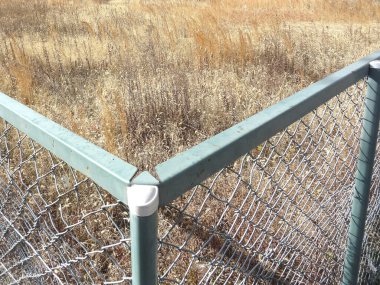 Kuru çim tarlasına karşı metal zincirli çitleri gösteren yakın plan.