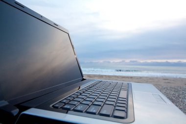 Gün batımında sahilde dizüstü bilgisayarı kapat.