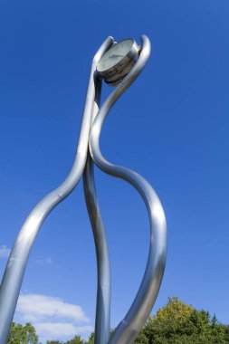 Parlak metal heykel parlak mavi gökyüzü arkaplanına çarpıyor