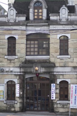 Büyük pencereleri ve dekoratif unsurları olan eski taş bina.