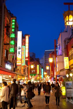 Turistler ve yerel halk, gece kentte sokak yemekleri ve dükkanlarla yürüyorlar.        