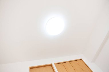 Tavan lambası ve ahşap kapısı olan boş bir oda. 