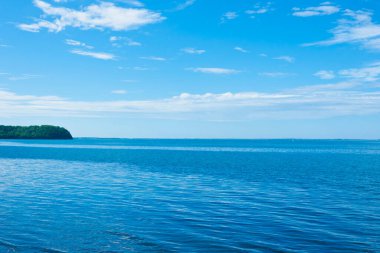 Mavi gökyüzü, denizin üzerinde beyaz bulutlar. Yaz manzarası.