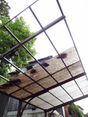 Bulutlu gökyüzünün altında delikleri olan hasarlı çatı