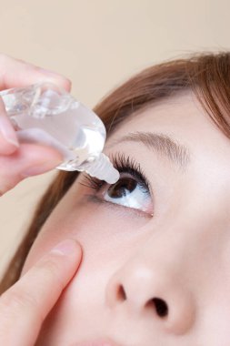 Göz damlası tutan genç bir kadın, stüdyo fotoğrafı.  