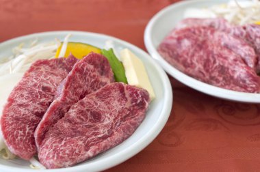 Beyaz tabakta taze kesilmiş et ve sebzelerin yakın plan görüntüsü.