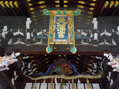 Renkli oymalar ve dekoratif yazılar içeren süslü ahşap bir çatı.