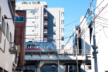 Şehir treni mavi gökyüzünün altındaki yüksek binaların arasından geçiyor.