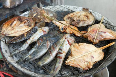 Grilling various fish on charcoal barbecue