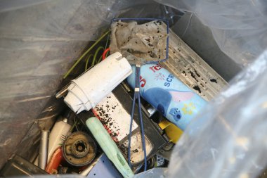 Atılmış ev eşyaları ve çöpler plastik çöp kutusunu dolduruyor.