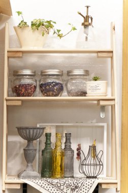 Ahşap rafta cam kavanozlar ve şişeler var.