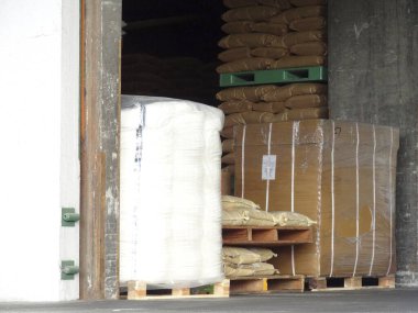 Yığılmış paletler endüstriyel deponun kapısında paketlenmiş mallar tutuyor.