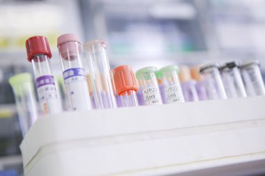 Beyaz plastik rafta çeşitli laboratuvar test tüpleri var.