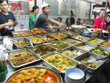Kalabalık marketlerde çeşitli sokak yemekleri servis eden insanlar.