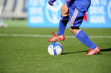 Spor giyim sektöründe futbol oyuncusunun bacakları çimlerin üzerinde top oynuyor.                 