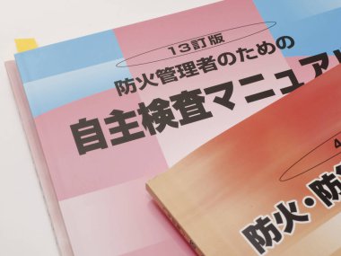 Yakından bakınca renkli Japon yangın güvenlik kitapçıklarının üst üste dizildiğini görüyoruz.